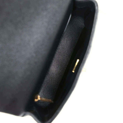 Black leather interior edge of mini flap bag with small gold-tone detail.
