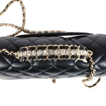 Close-up of quilted flap bag front with rhinestone chain and gold-tone hardware details