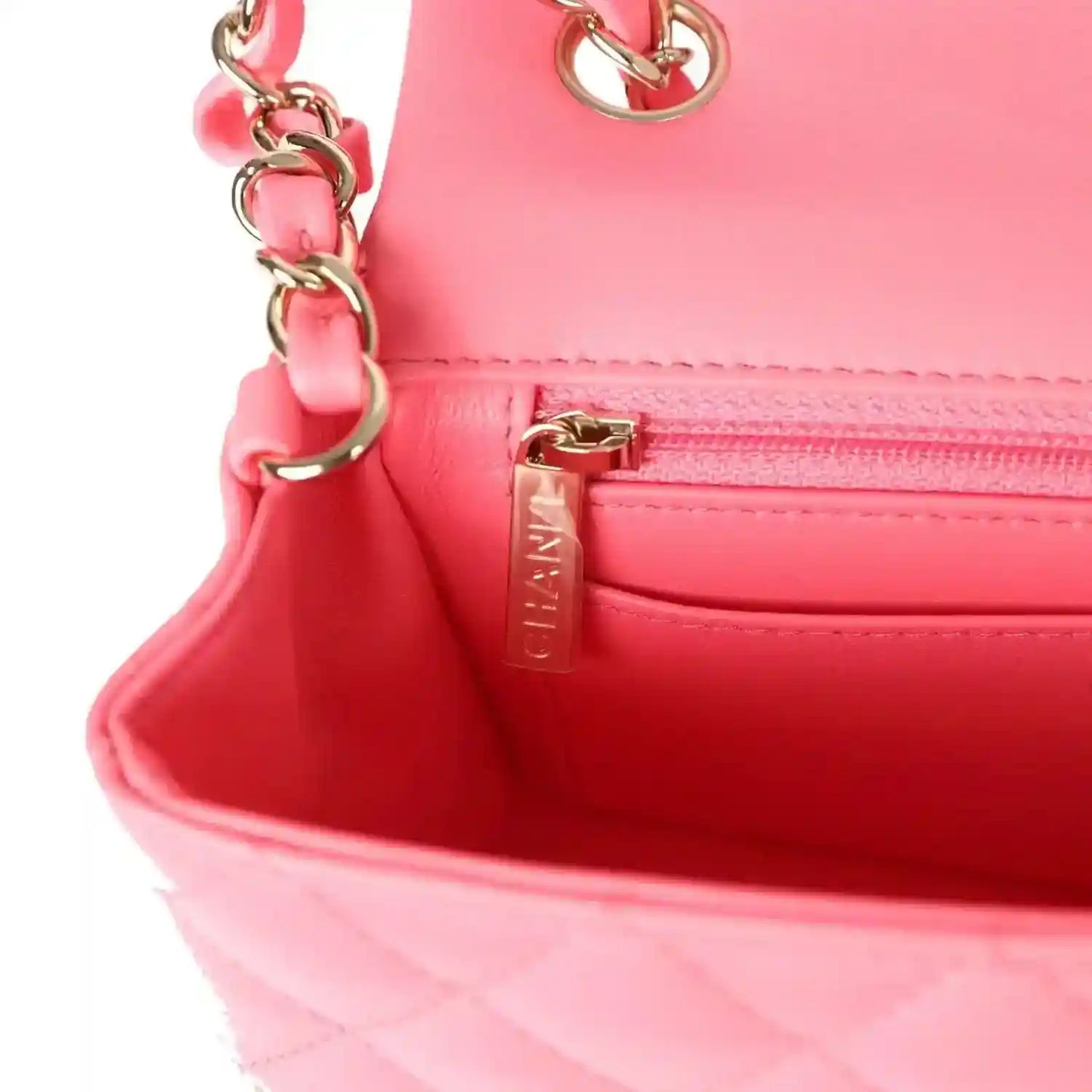 Hot pink interior pocket of mini flap bag with zipper and metal pull tab