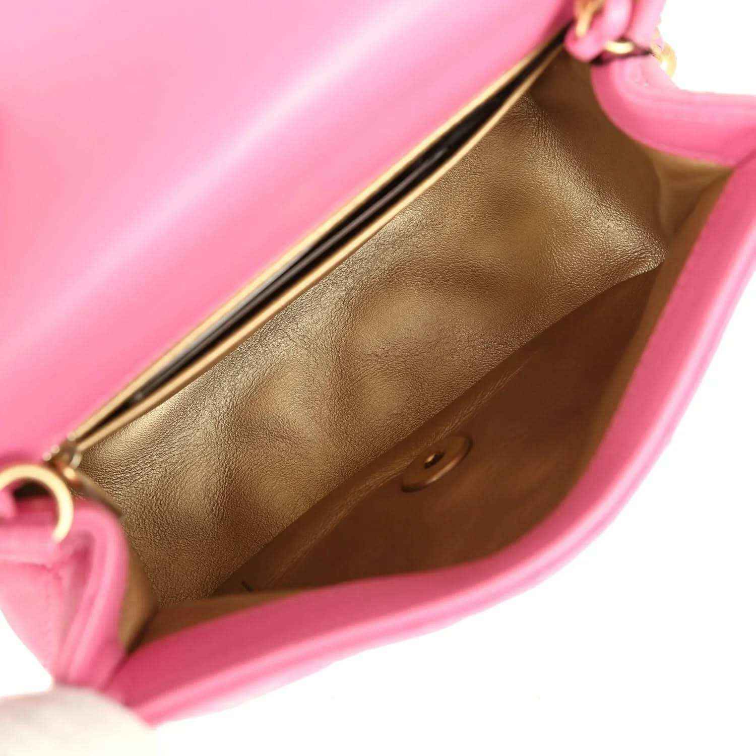 Pink mini flap bag interior with tan leather lining and gold-tone frame edge.