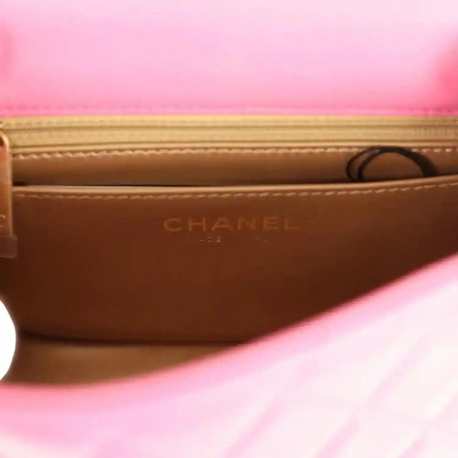 Mini flap bag interior lining with CHANEL embossed on tan leather base.
