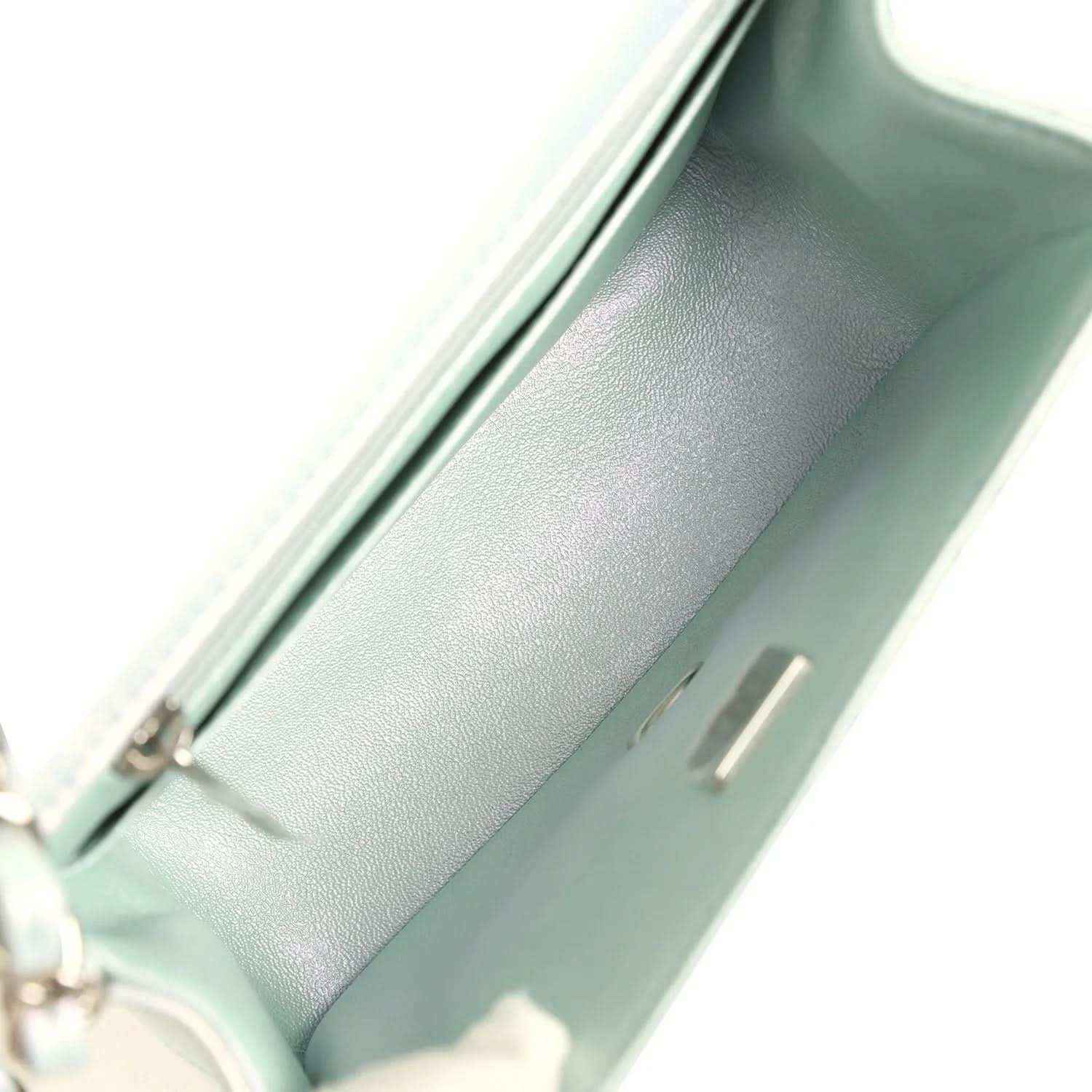 Interior of mini square flap bag in iridescent light blue leather with stitched edge and pocket