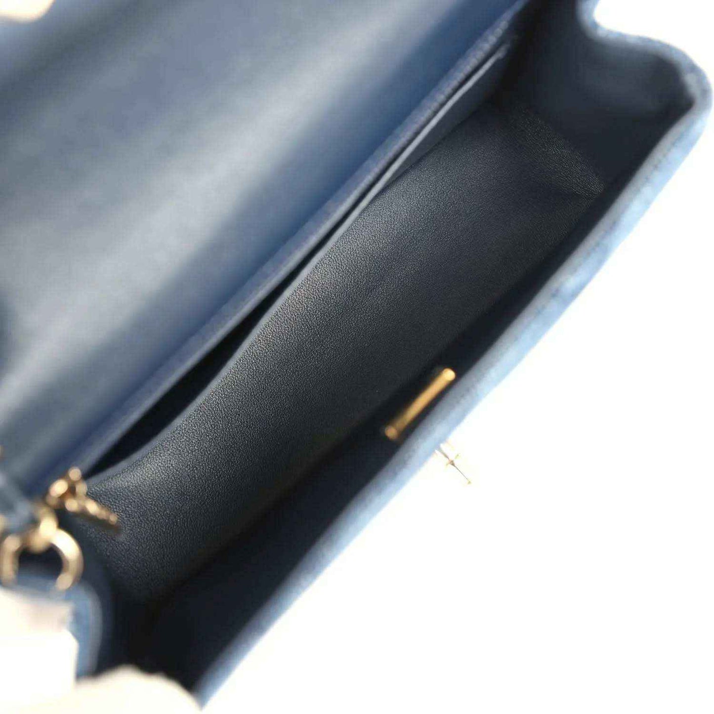 Chanel mini flap bag interior view, blue leather lining and gold clasp hardware