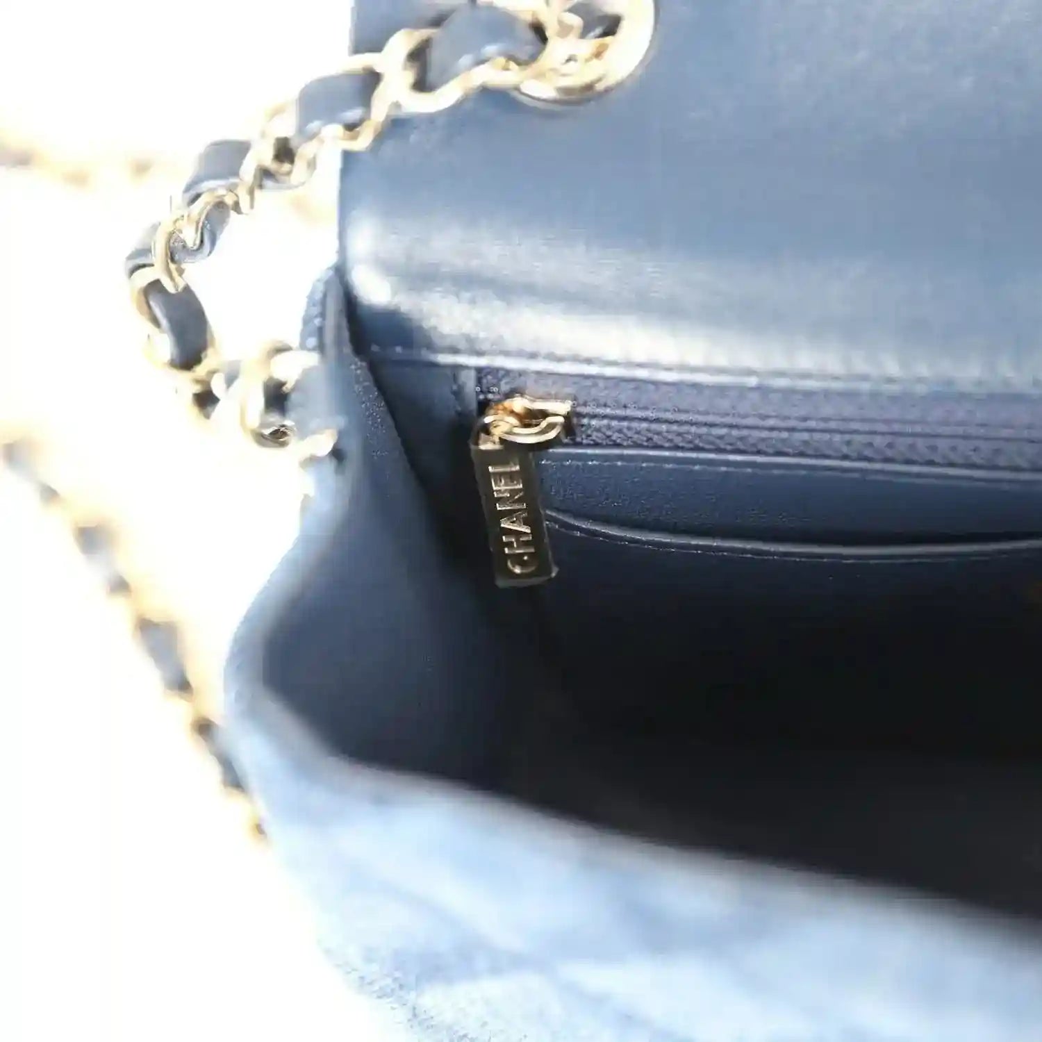 Chanel mini flap bag close-up, blue leather pocket with gold zipper pull