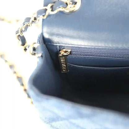 Chanel mini flap bag close-up, blue leather pocket with gold zipper pull
