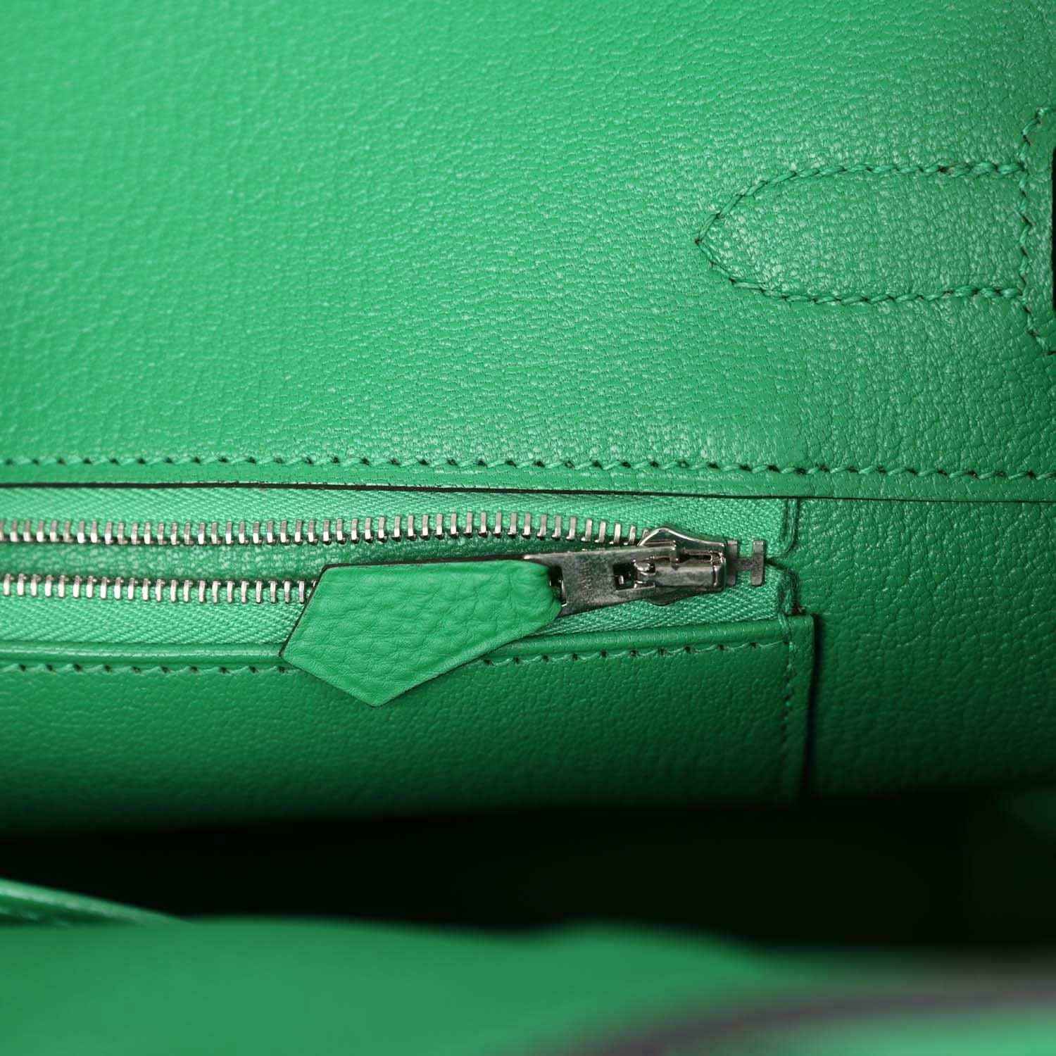 Green leather handbag close-up of zipper pull and stitched seam detail