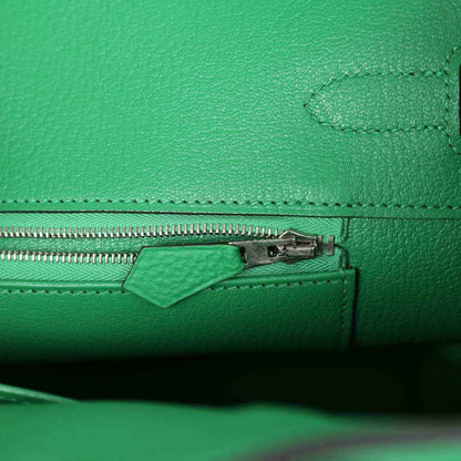 Green leather handbag close-up of zipper pull and stitched seam detail