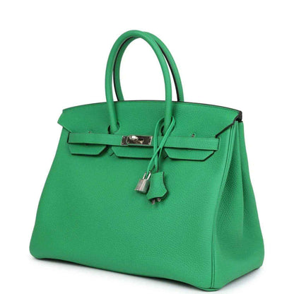 Green leather handbag with front flap, metal lock, and key charm on the top handle