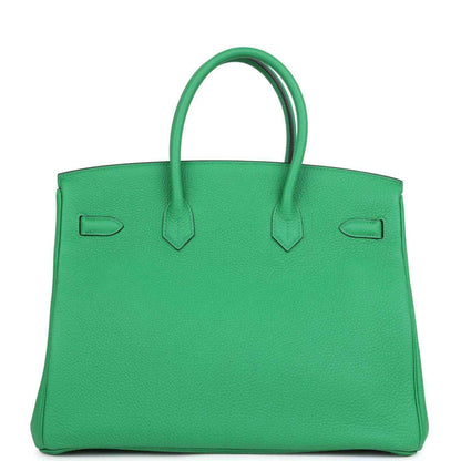 Green leather top-handle handbag with rear panel and inset pocket details
