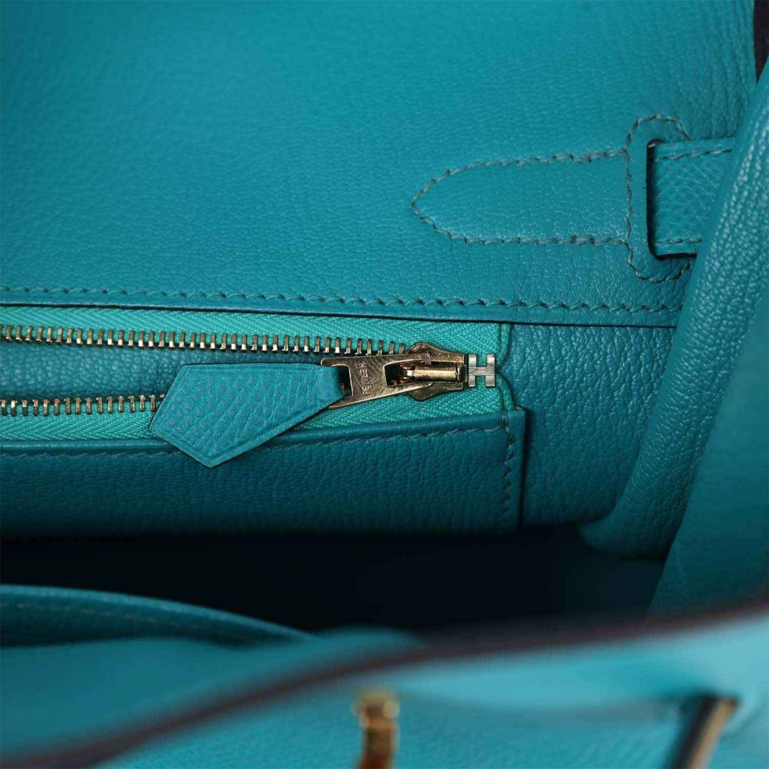 Blue peacock leather zip pocket with gold zipper pull, tab, and stitched seams