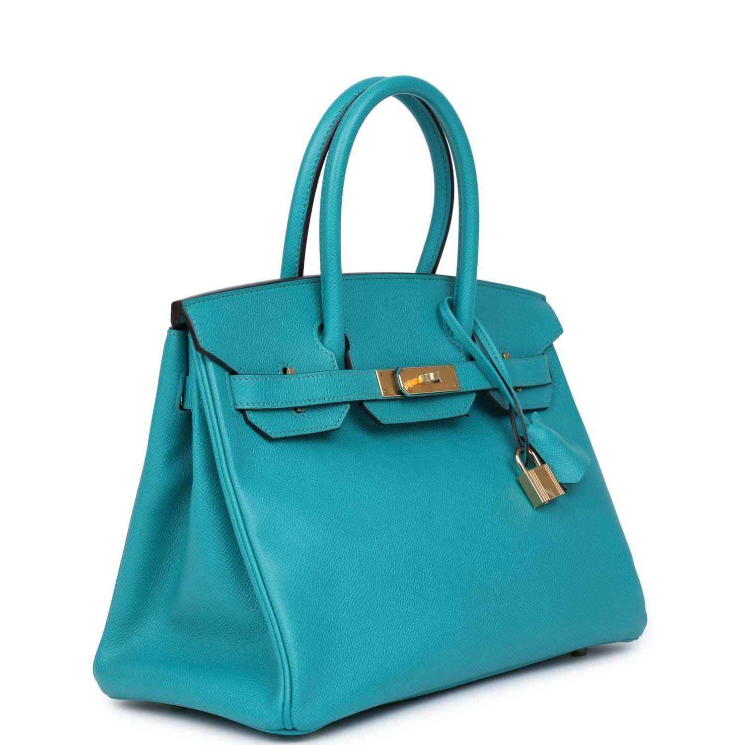 Blue peacock leather handbag with top handles, front lock hardware, and structured sides