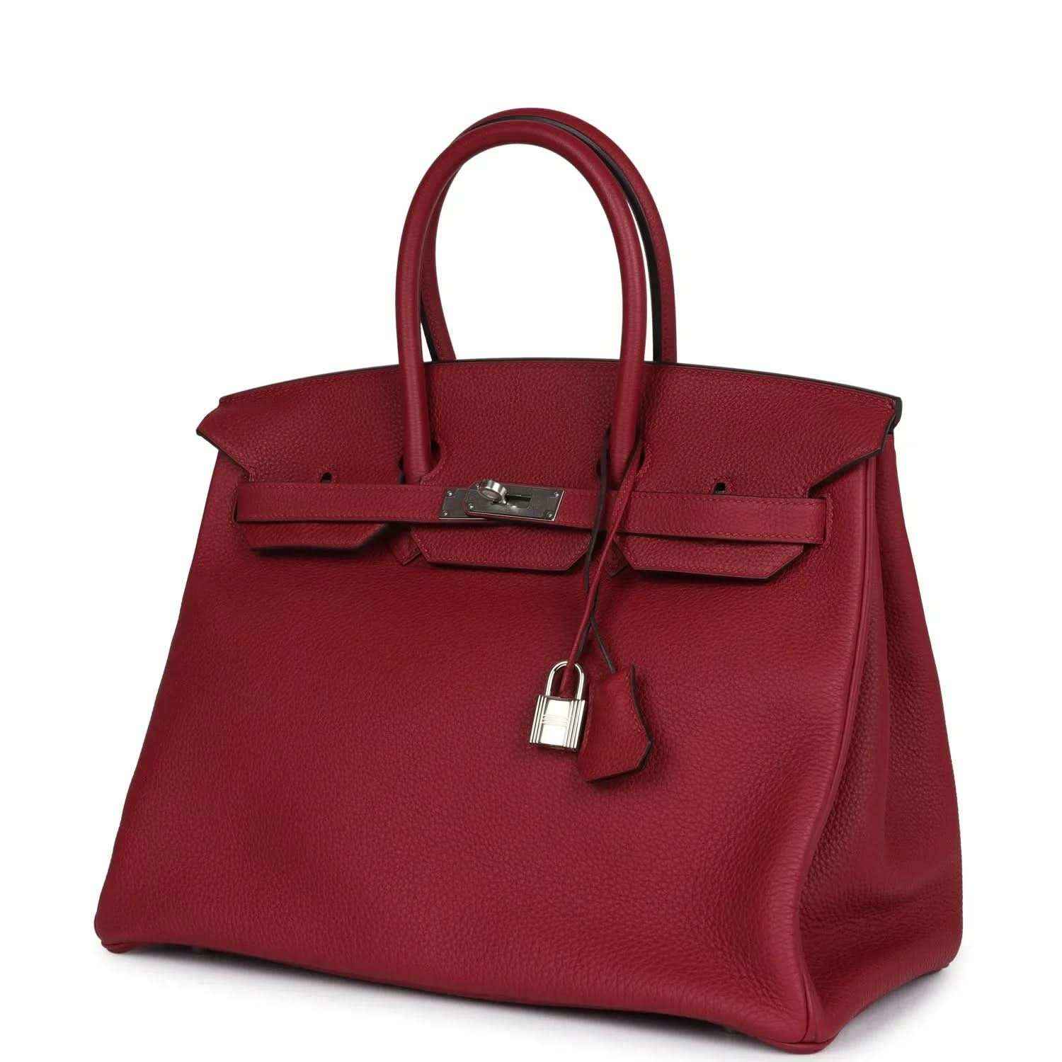 Red leather Birkin-style handbag with front clasp and hanging padlock charm, angled view
