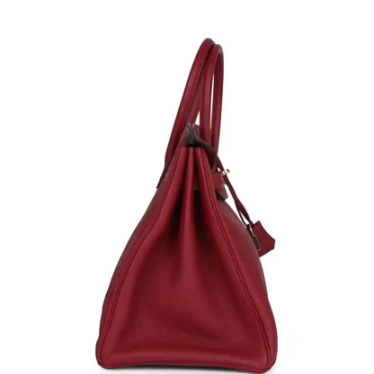 Red leather handbag in triangular side view with top handles and padlock accessory