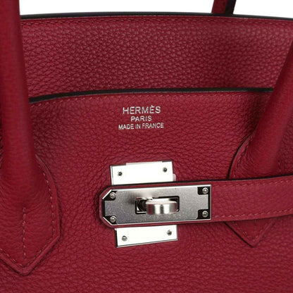 Red leather handbag with front turn-lock clasp and engraved “Hermès Paris Made in France”