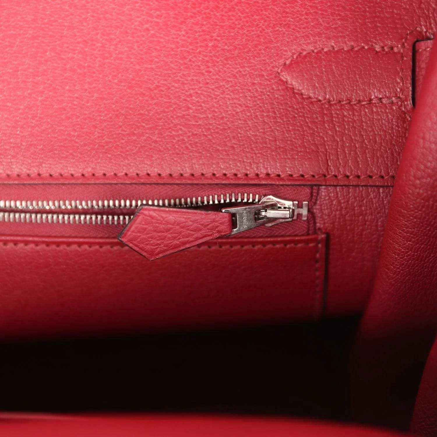 Red leather handbag interior with zipper track and small pull tab near side seam