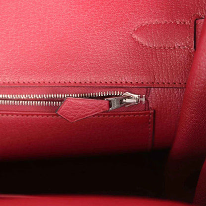 Red leather handbag interior with zipper track and small pull tab near side seam