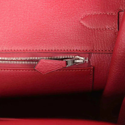 Red leather handbag interior with zipper track and small pull tab near side seam