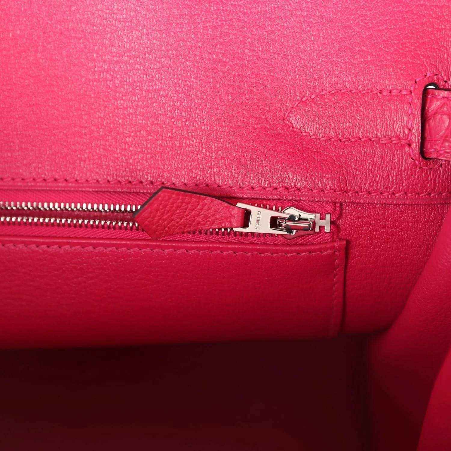 Pink Birkin handbag zipper close-up with metal pull and stitched panel.