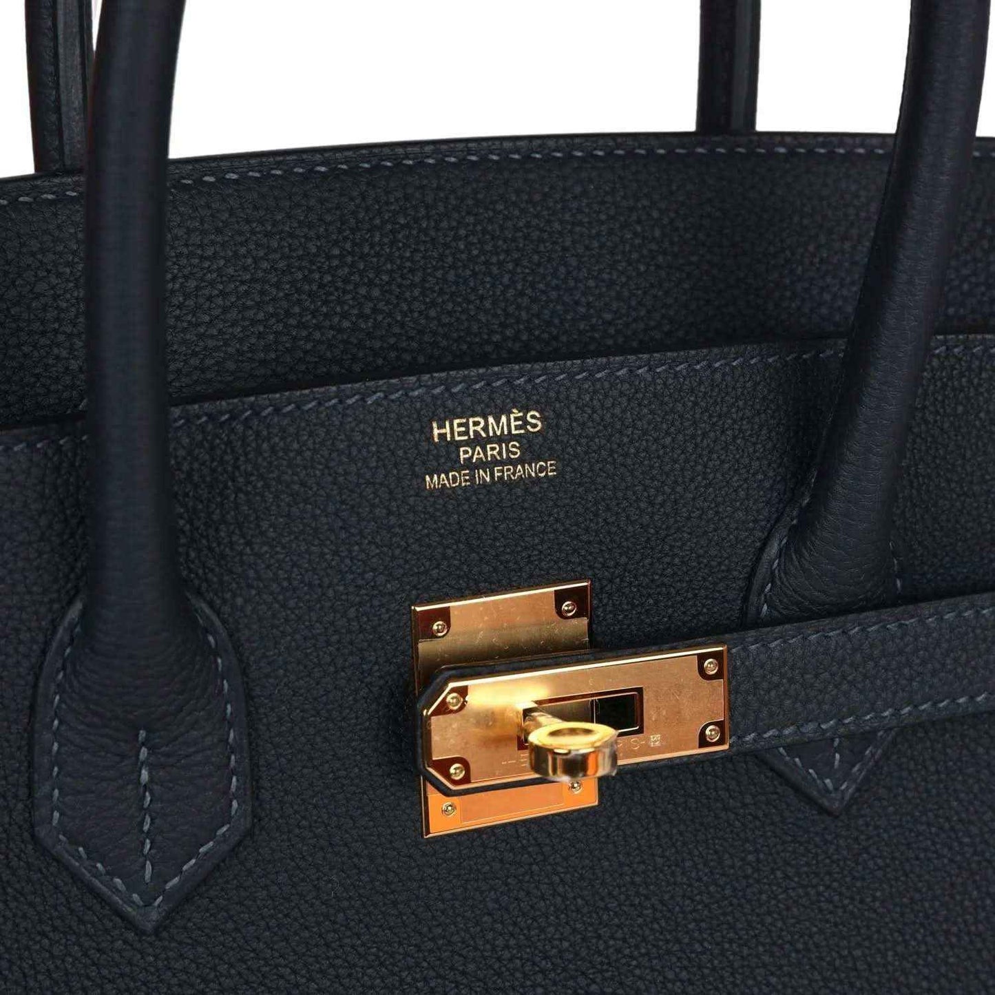 Birkin handbag interior pocket with gold clasp and stitched leather trim, dark color