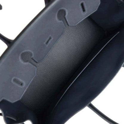 Leather handbag close-up with textured finish and dark cutout details, dark color