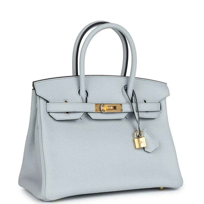 Pale blue leather handbag with gold hardware, top handles, and front flap with lock