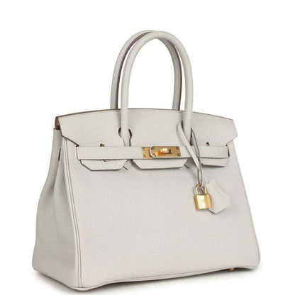 Light gray leather handbag with gold front clasp, top handles, hanging lock charm