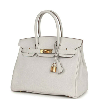 Light gray leather handbag with gold front clasp, top handles, hanging lock charm