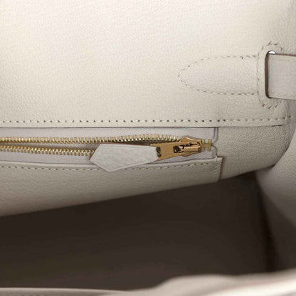 Light gray leather handbag with gold zipper pull and inside tab hardware