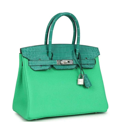 Green leather handbag with crocodile texture, top handles, front flap and dangling lock charm