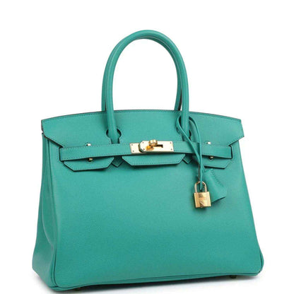 Green leather handbag with top handles, front flap and hanging gold-tone padlock