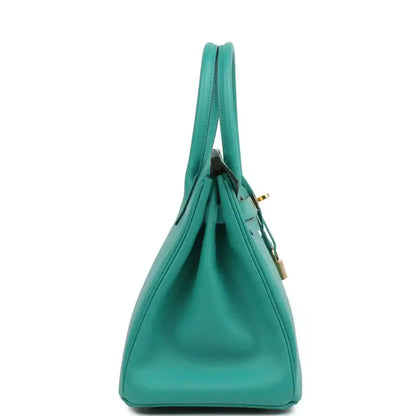Green leather handbag shown from the side with structured body and top handles