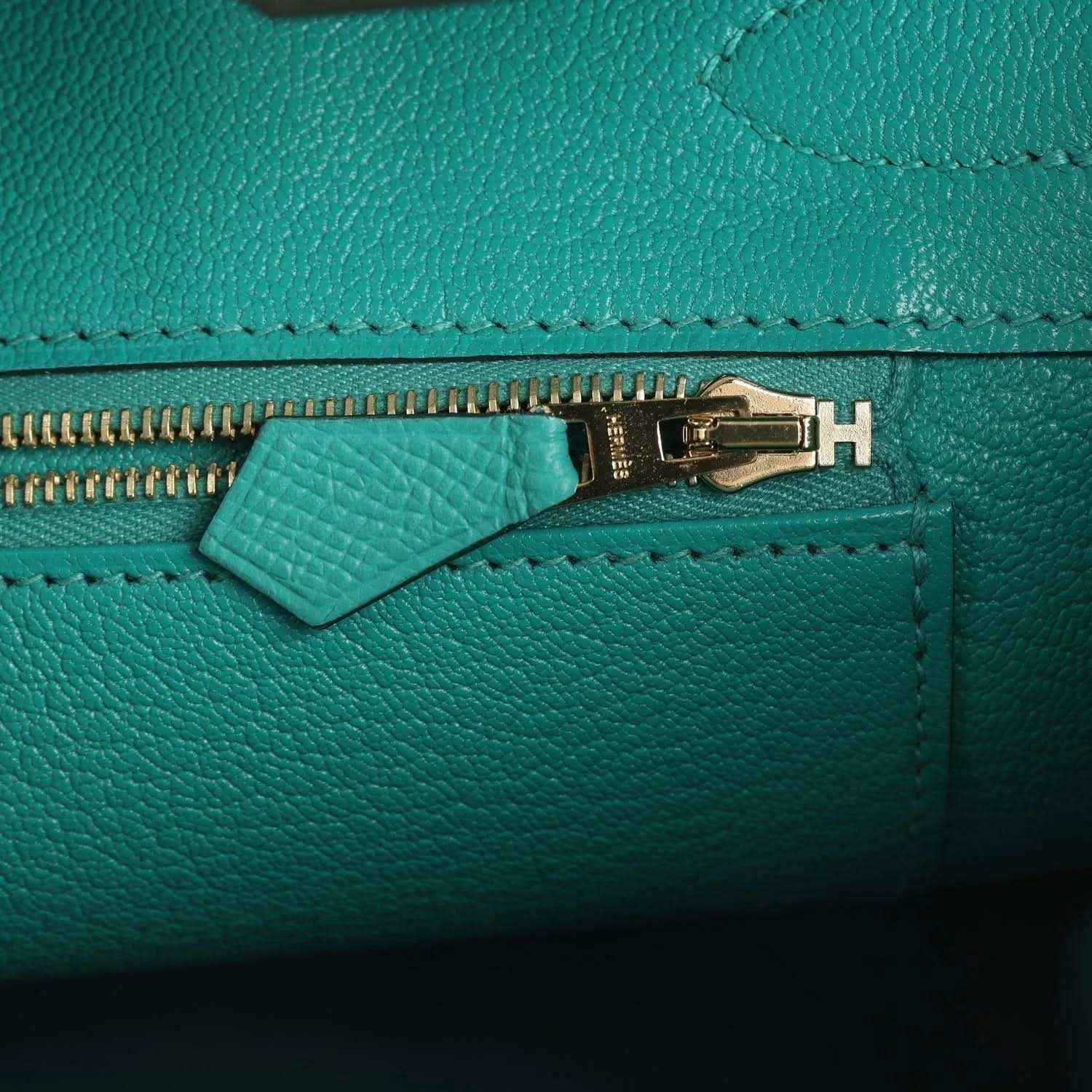 Green leather handbag zipper with gold-tone hardware and stitched leather edge