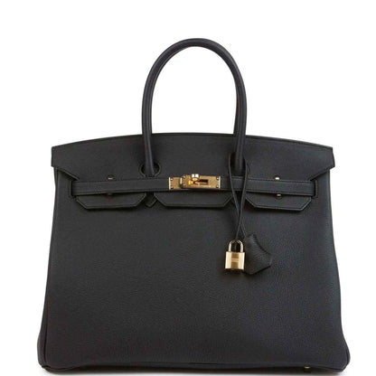Black leather handbag with gold turn-lock, front flap, and top handles