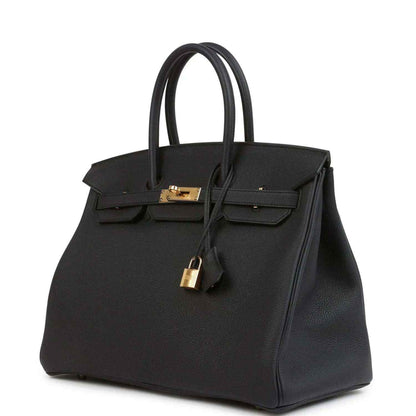 Black leather handbag with gold turn-lock and front flap, angled view