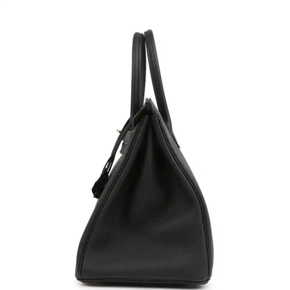 Black leather handbag with two top handles and structured side profile