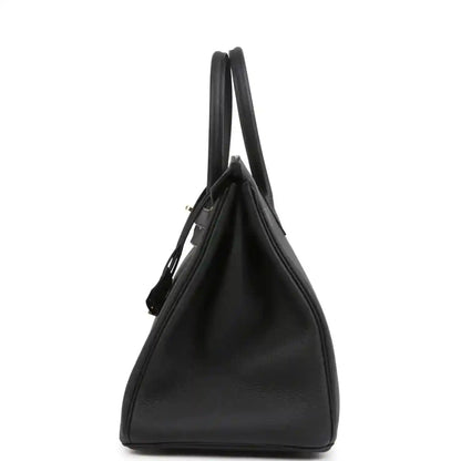 Black leather handbag with two top handles and structured side profile