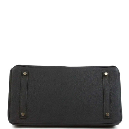 Black leather handbag with reinforced base corners and side handle attachments