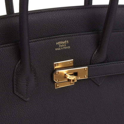 Black leather handbag interior pocket with HERMÈS PARIS stamp and gold clasp