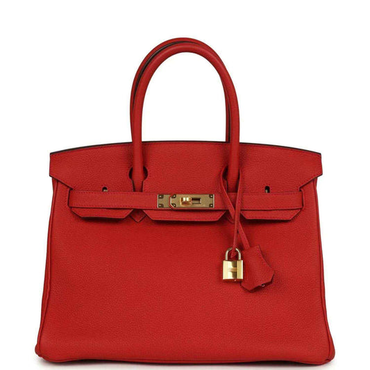 Red leather handbag with gold front clasp, lock, and top handles