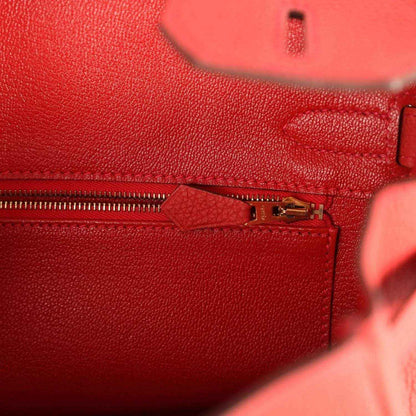 Red leather handbag close-up of gold clasp and zipper pull