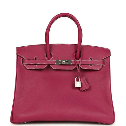 Pink Epsom leather handbag with top handles, front belt clasp, and hanging padlock charm.