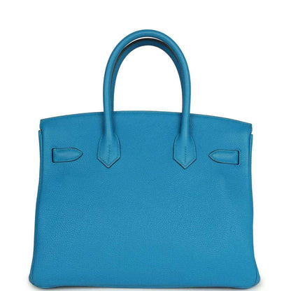 Blue leather handbag with front exterior pockets and top handles