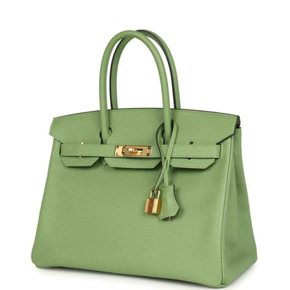 Green leather handbag with top handles, front flap, gold-tone clasp, and lock charm