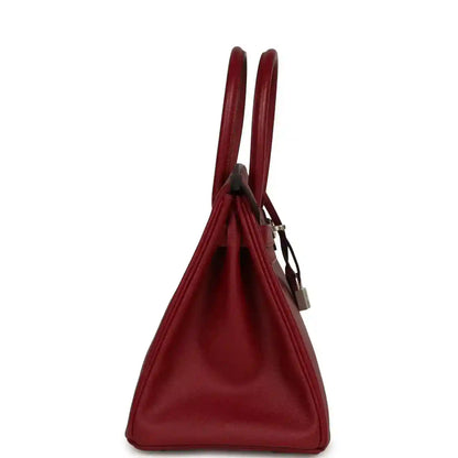 Red leather handbag with top handles and hanging lock, side view