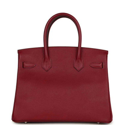 Red leather handbag with structured front, twin handles and silver hardware feet