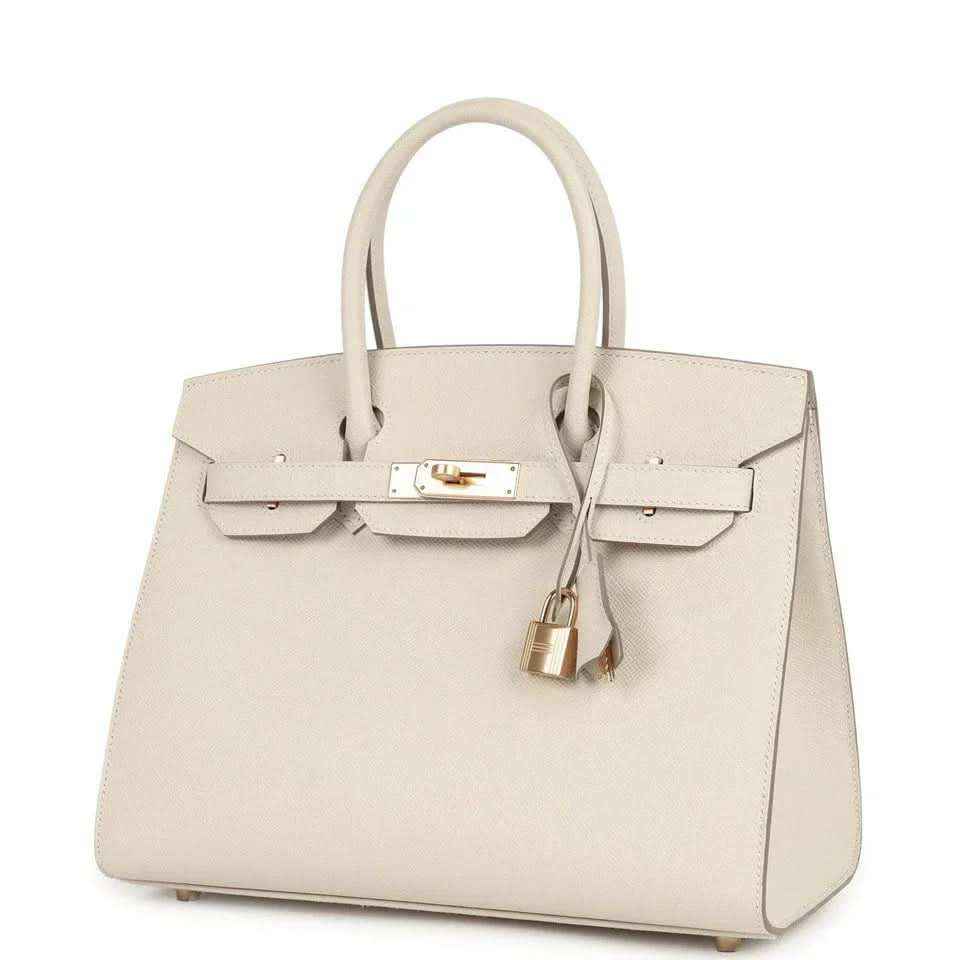 Light cream leather handbag with gold front lock, top handles, and hanging padlock