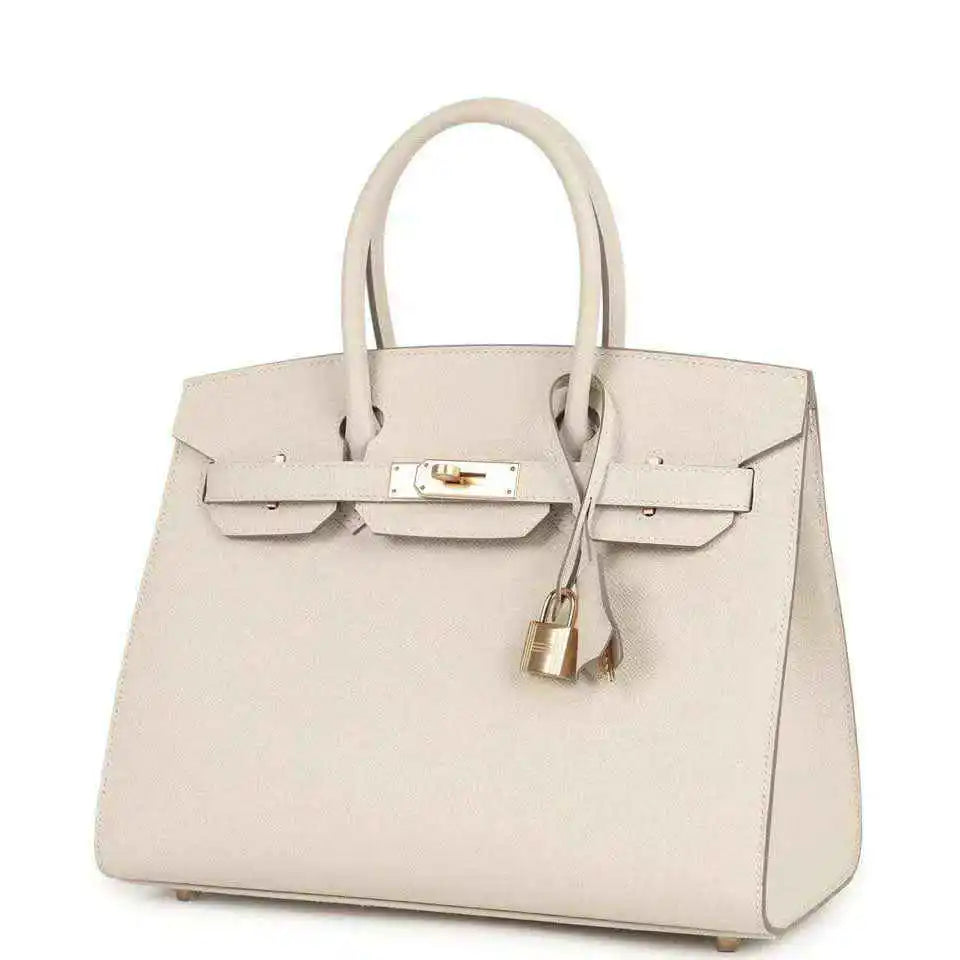 Light cream leather handbag with gold front lock, top handles, and hanging padlock