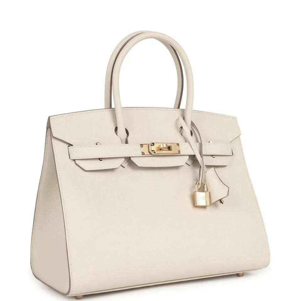 Light cream leather handbag with gold front lock, top handles, and hanging padlock