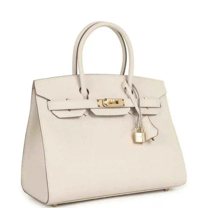 Light cream leather handbag with gold front lock, top handles, and hanging padlock