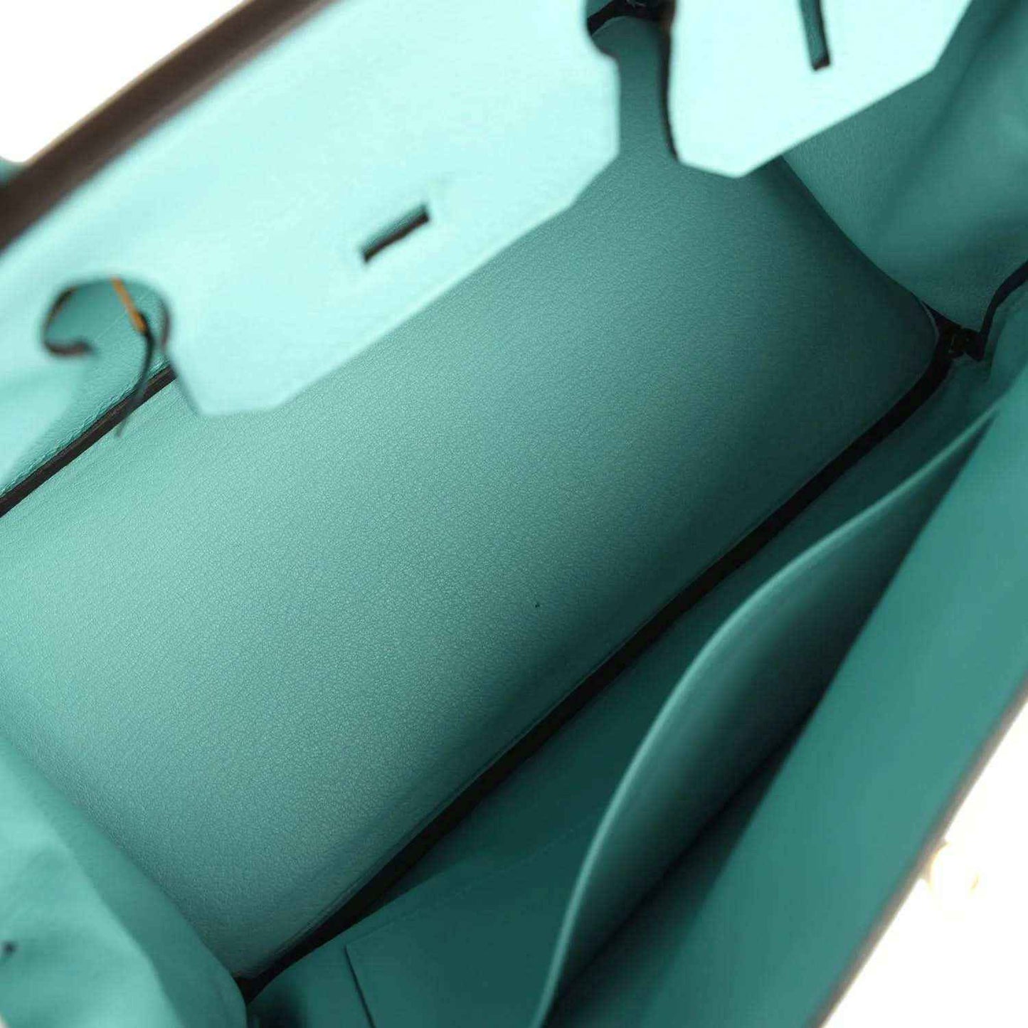 Teal leather handbag interior view with front wall seam lines and structured inner base